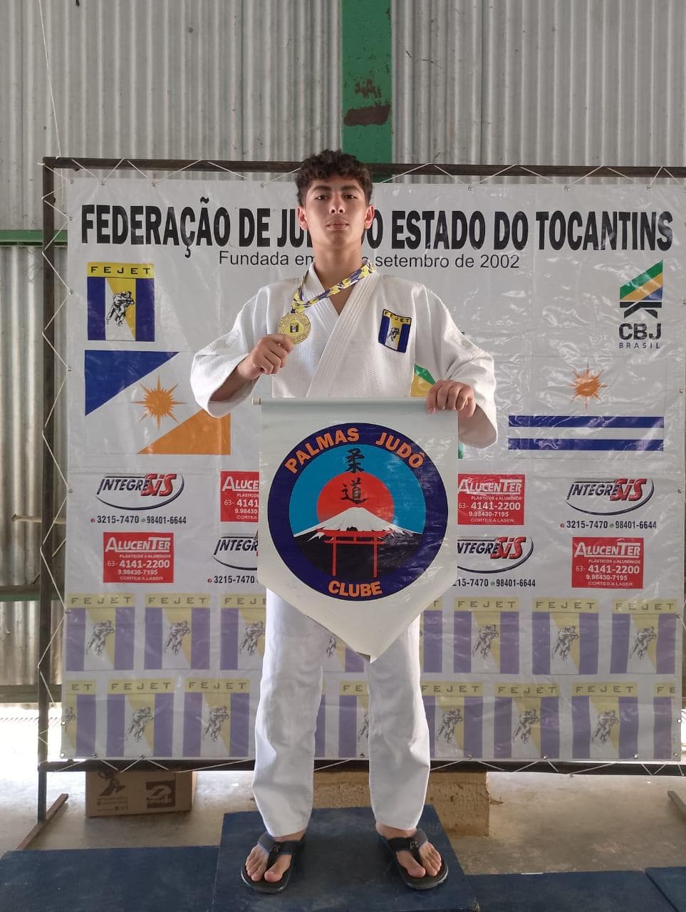Atleta em primeiro lugar segurando a bandeira do clube