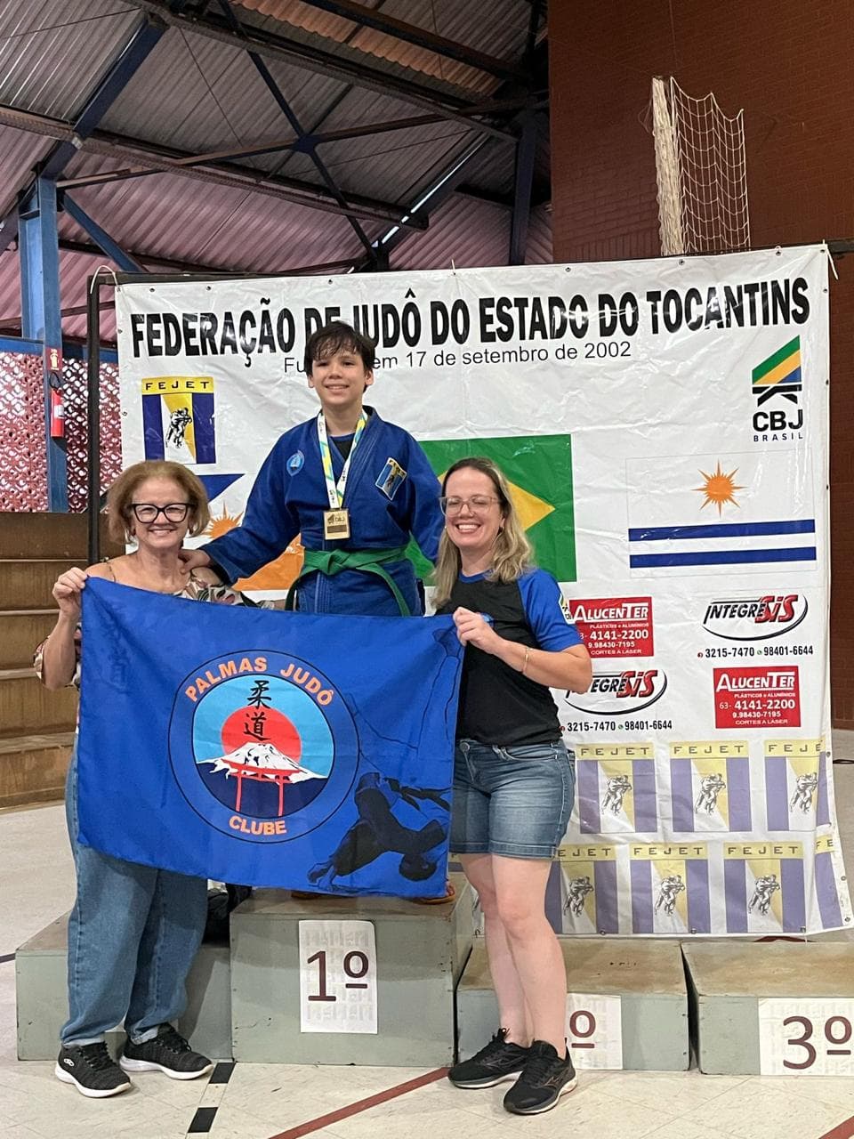 Atleta no pódio com a bandeira do Palmas Judô Clube